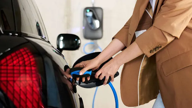 EKZ Kundin lädt ihr Elektroauto von der Wallbox in ihrem Carport. Sie konnte dank Fördergelder Kosten sparen.