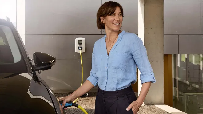 EKZ Kundin lädt ihr Elektroauto von der Wallbox in ihrem Carport. Sie konnte dank Fördergelder Kosten sparen.