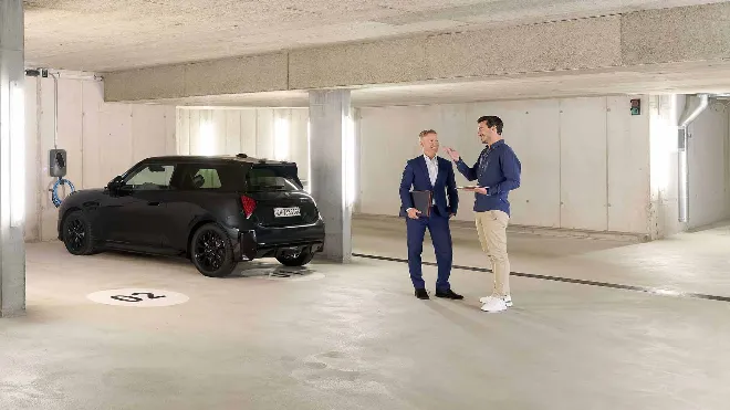 Eine Frau in der Tiefgarage eines Mehrfamilienhauses lädt ihr Elektroauto an einer Ladestation. Die Ladestation ist Teil der EKZ Ladelösung, die in dieser Immobilie dank Fördergelder vergünstigt umgesetzt werden konnte.