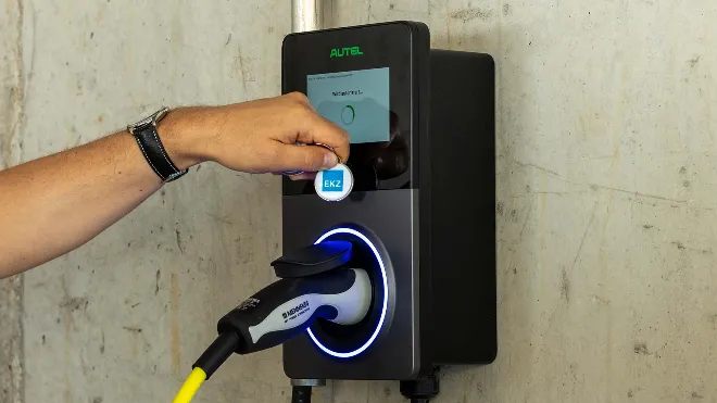 Eine Person hält den EKZ Zugangschip an den RFID-Leser der Ladestation und schaltet damit den Ladevorgang frei.