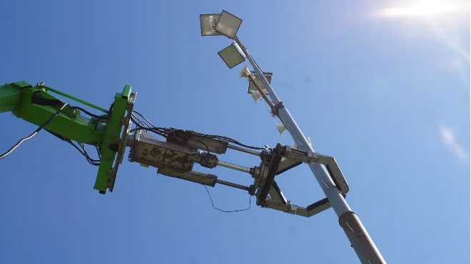 Ein Mast auf einem Fussballplatz wird geprüft.