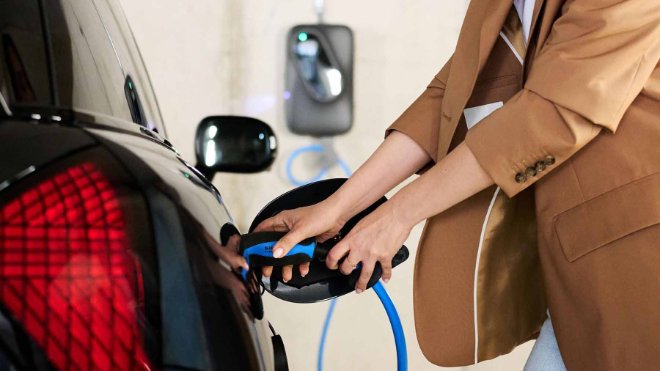 EKZ Kundin lädt ihr Elektroauto von der Wallbox in ihrem Carport. Sie konnte dank Fördergelder Kosten sparen.