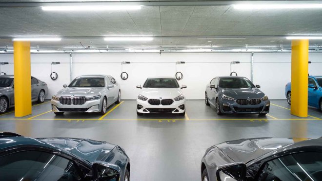 Mehrere geparkte Unternehmensfahrzeuge vor Ladestationen in einer Tiefgarage.