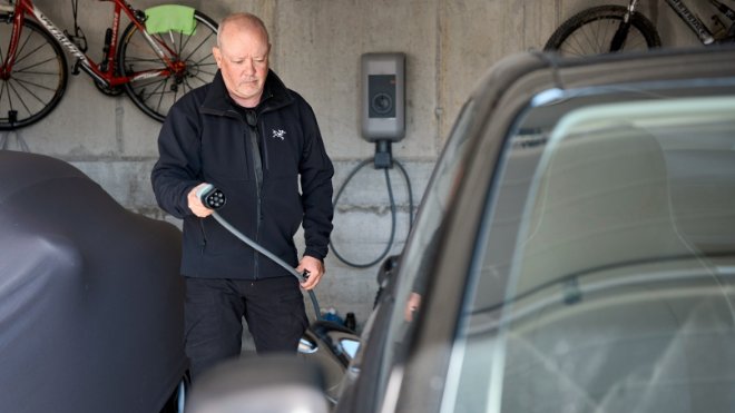 André Fehr vor seinem Smart mit dem Ladekabel in der Hand.