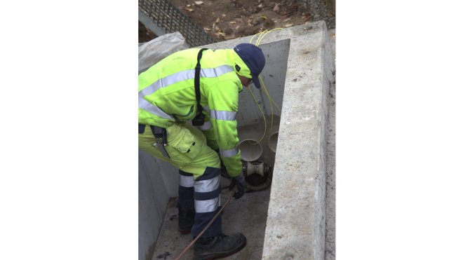 Mitarbeiter zieht Zugseil aus dem Kabelrohr