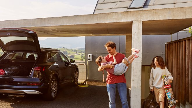 Familie am Herumtoben, beim Beladen des E-Autos